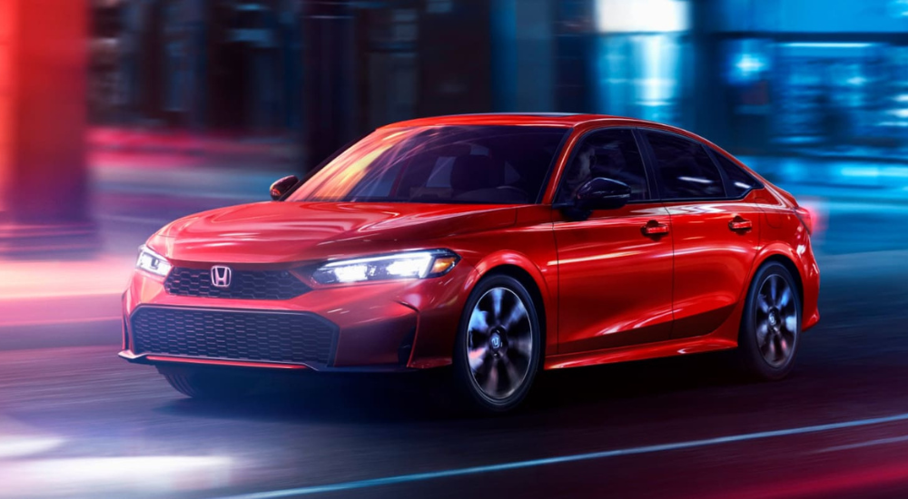 Red 2026 Honda Civic driving down a city street.