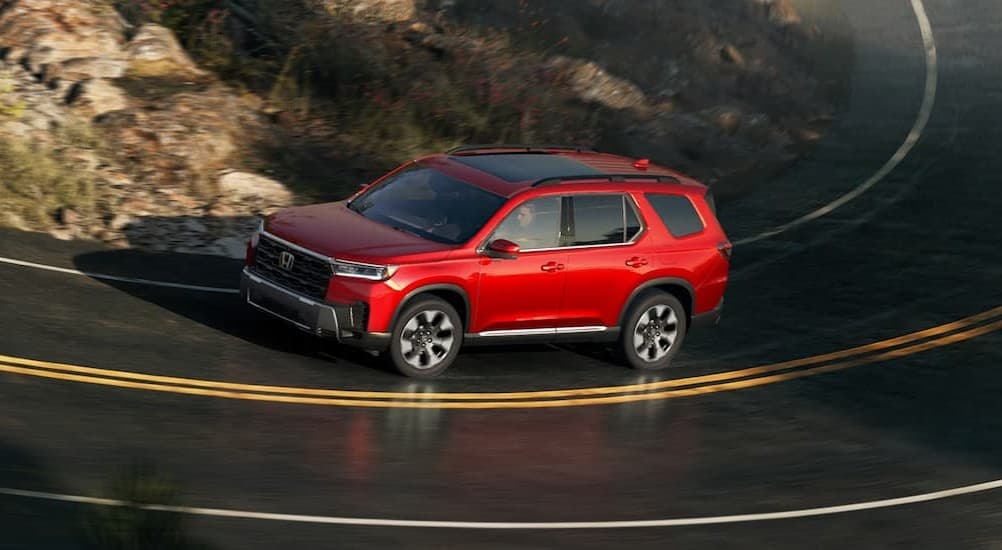 A red 2026 Honda Pilot driving to a Honda dealer near Bessemer.