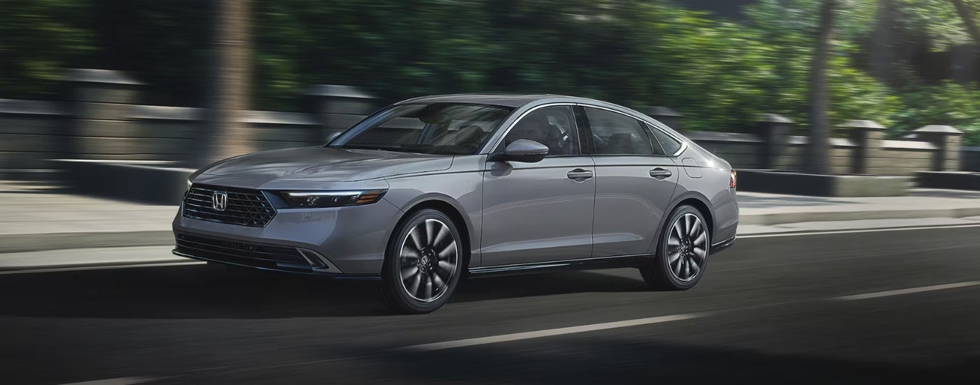 Grey 2025 Honda Accord Hybrid driving on a city street