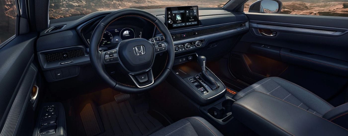 The black front interior of a 2026 Honda CR-V showing the steering wheel and infotainment display.