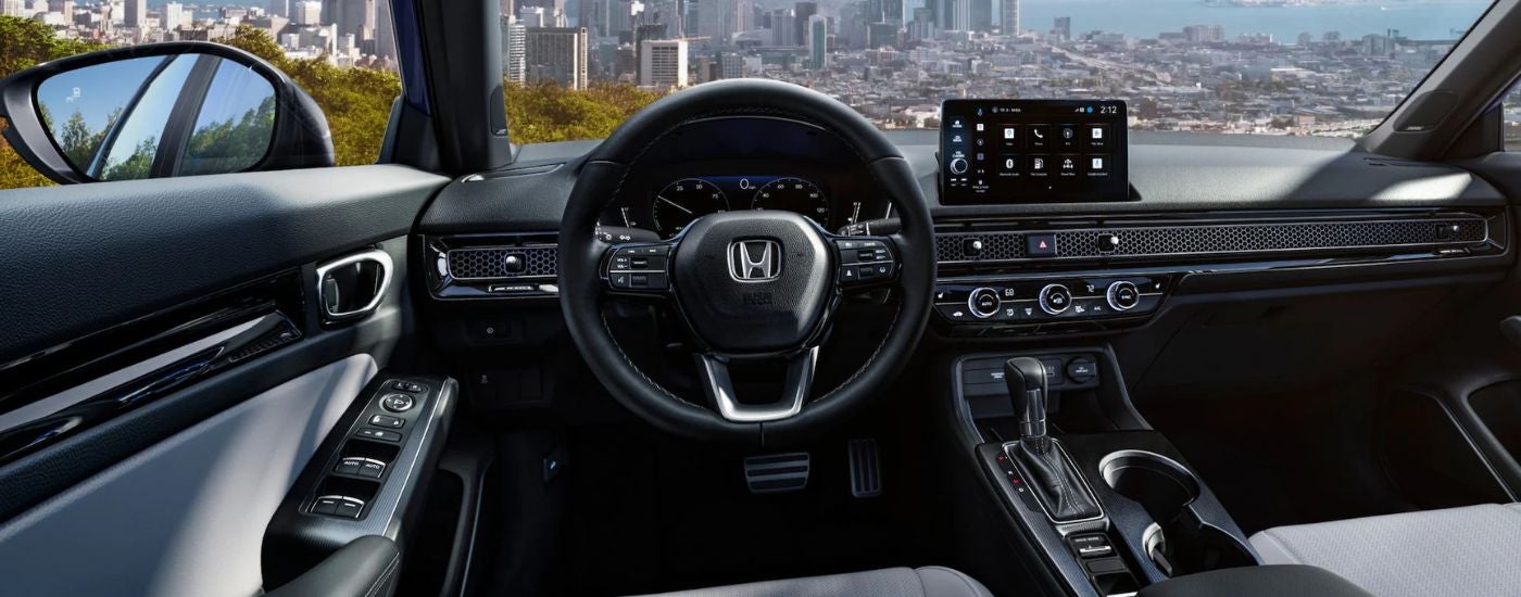 Front interior of a 2026 Honda Civic showing the steering wheel and infotainment from the driver's seat.