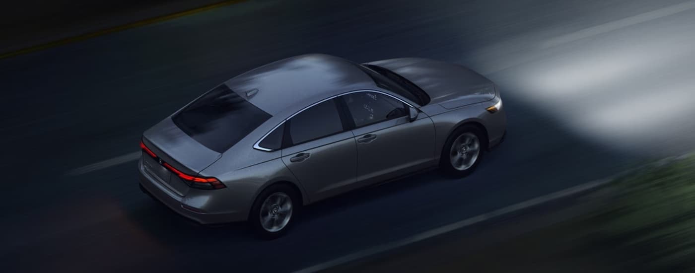 A gray 2026 Honda Accord driving down a road at night
