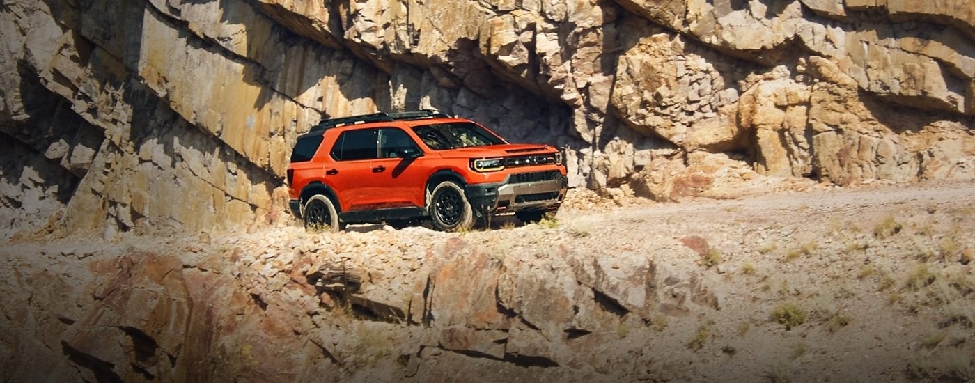 Orange 2026 Honda Passport Elite Trailsport driving off-road