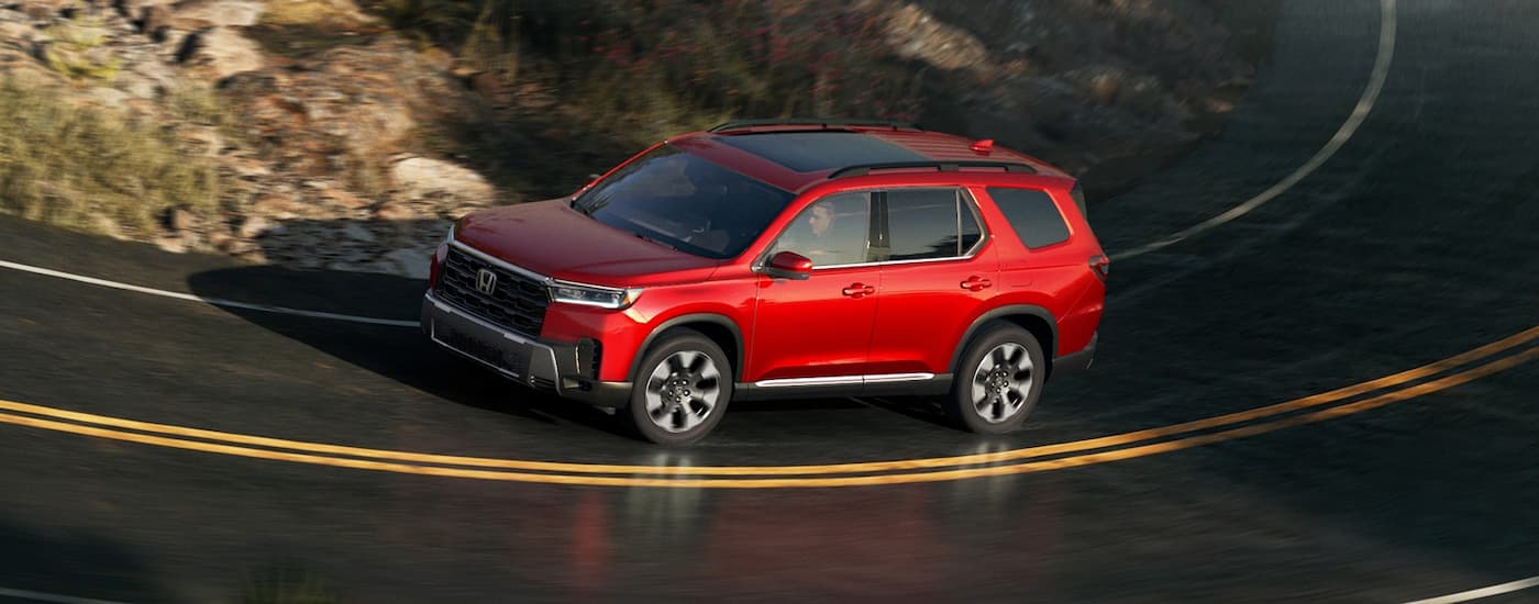 Red 2026 Honda Pilot driving on a winding road