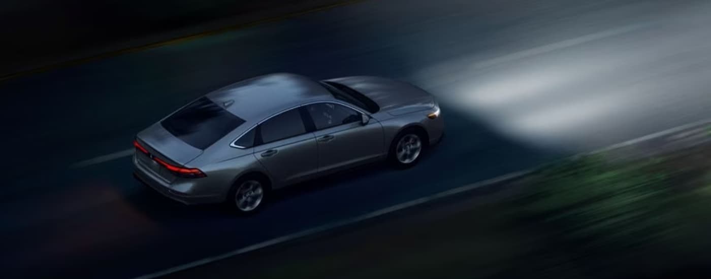 A silver 2025 Honda Accord driving at night.