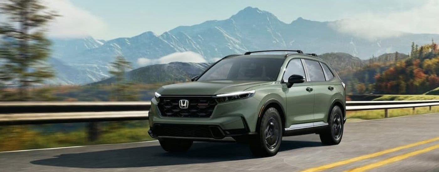 A green 2026 Honda CR-V driving on a highway.