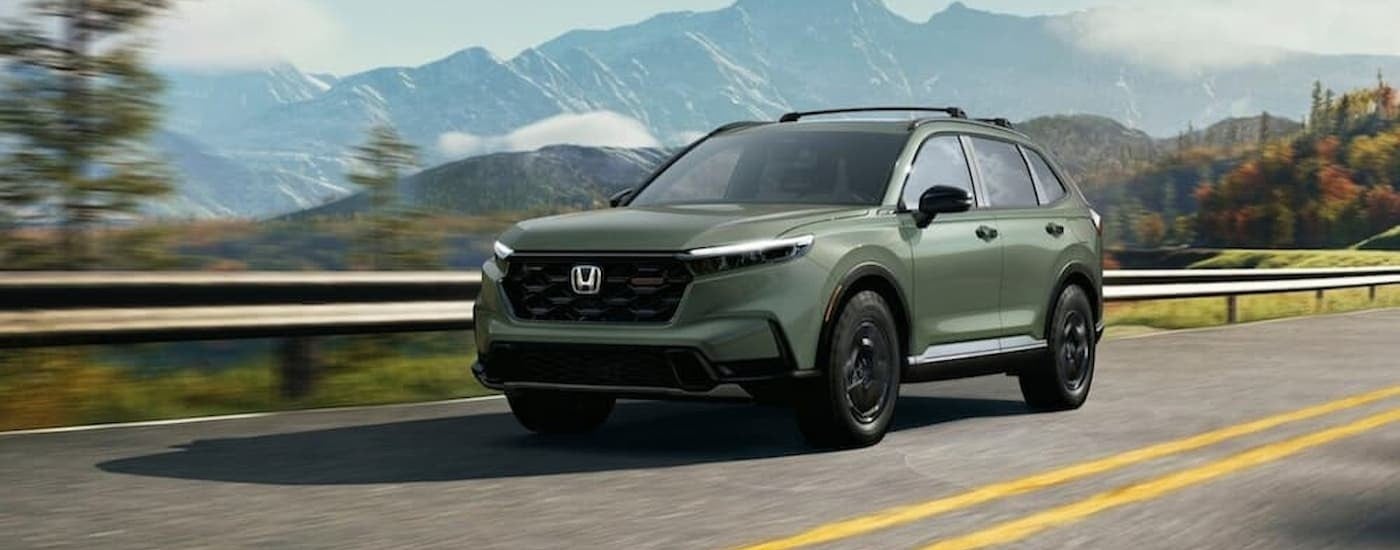 A green 2026 Honda CR-V driving on a highway.