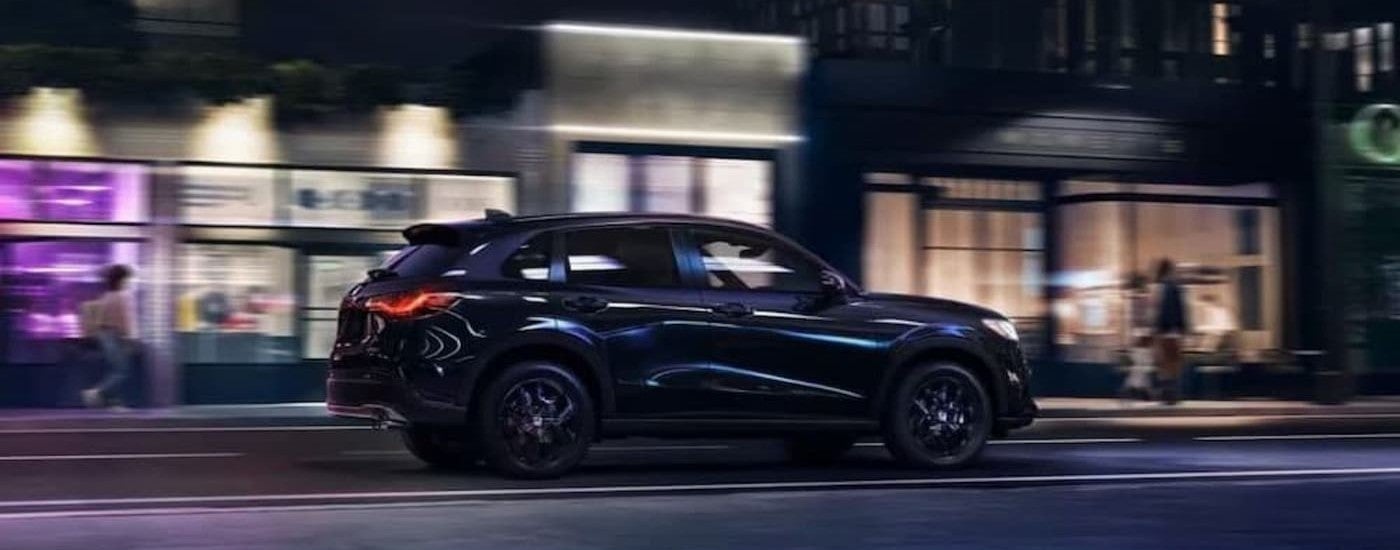 A black 2023 Honda HR-V driving in a city.