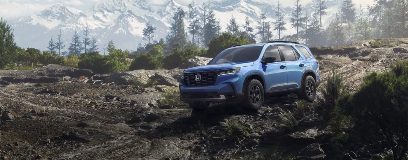 Blue 2025 Honda Pilot for sale driving on a dirt trail.