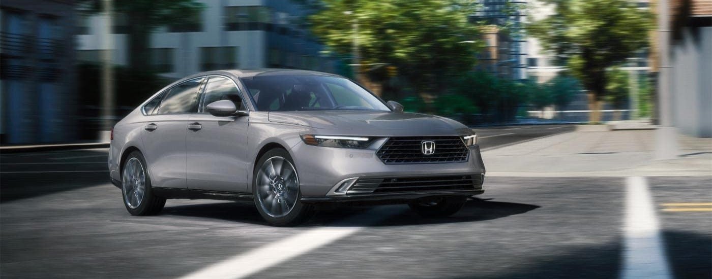 A silver 2026 Honda Accord Touring Hybrid driving in a city