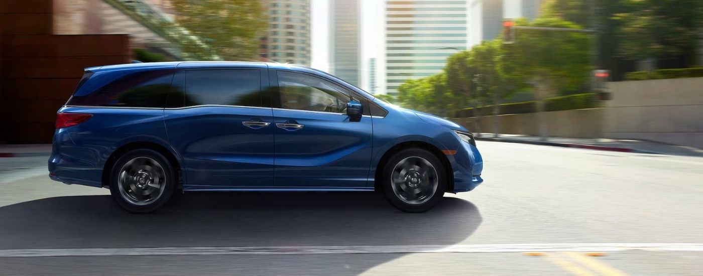 A blue 2025 Honda Odyssey for sale driving in a city