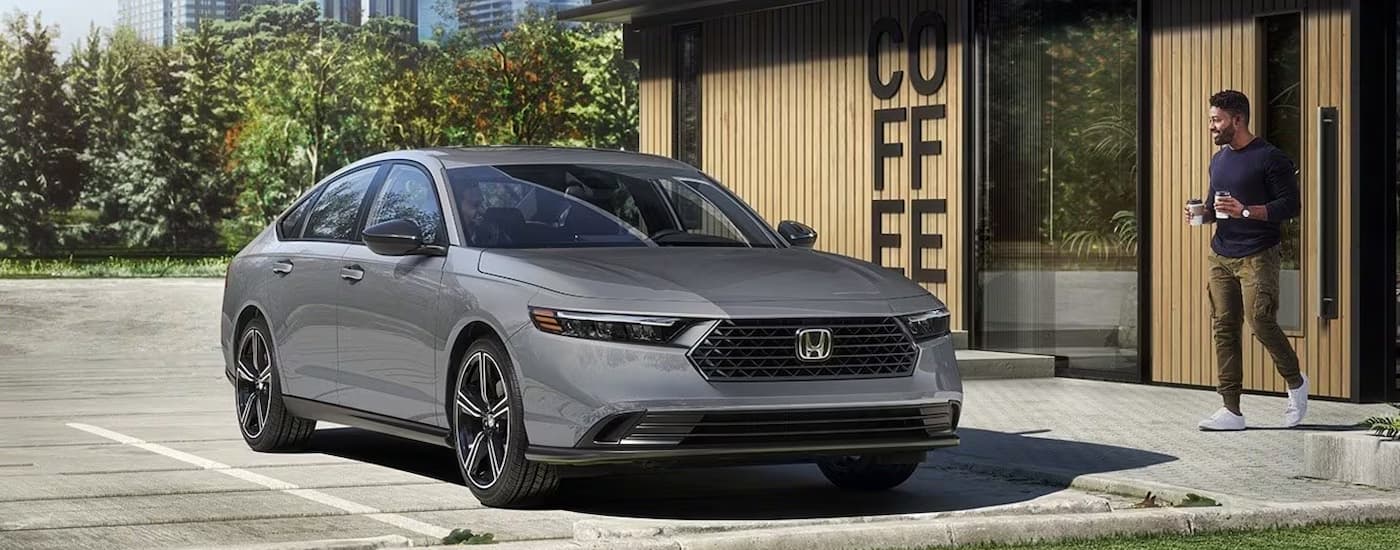 A silver 2026 Honda Accord Hybrid parked outside a coffee shop.